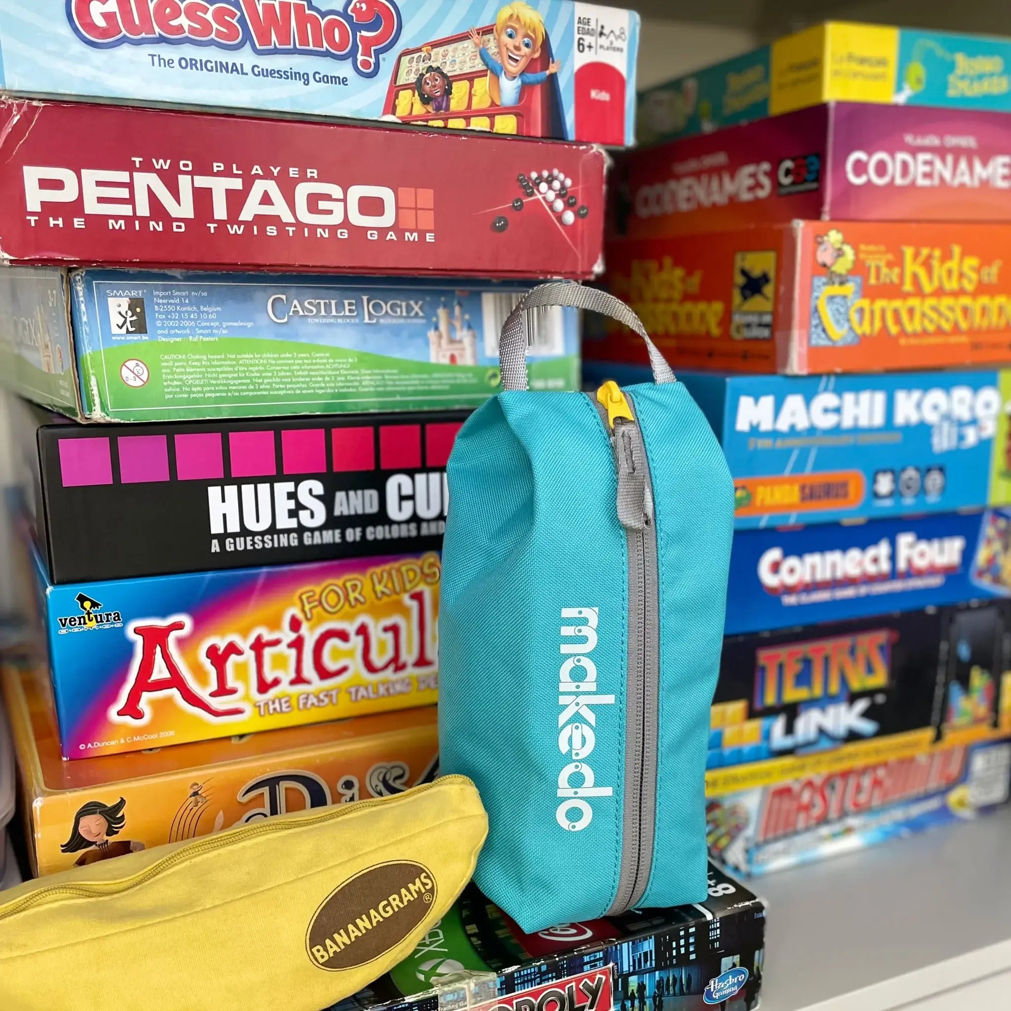 Stack of board game boxes with a blue Makedo bag in the foreground