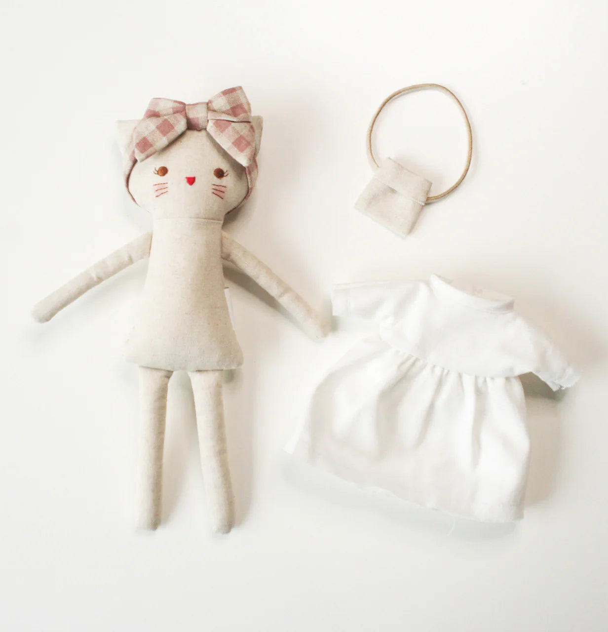 Fabric doll kitten with a checkered bow and a matching dress on a white background.