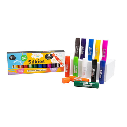 A set of Silkies Paint Sticks with 12 different colors displayed next to their packaging box.