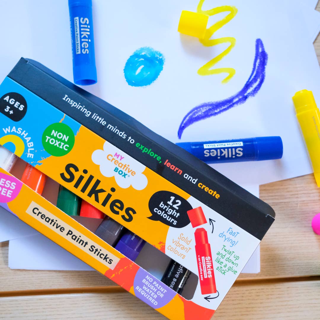 A set of Silkies Paint Sticks displayed with their packaging box with paper background.