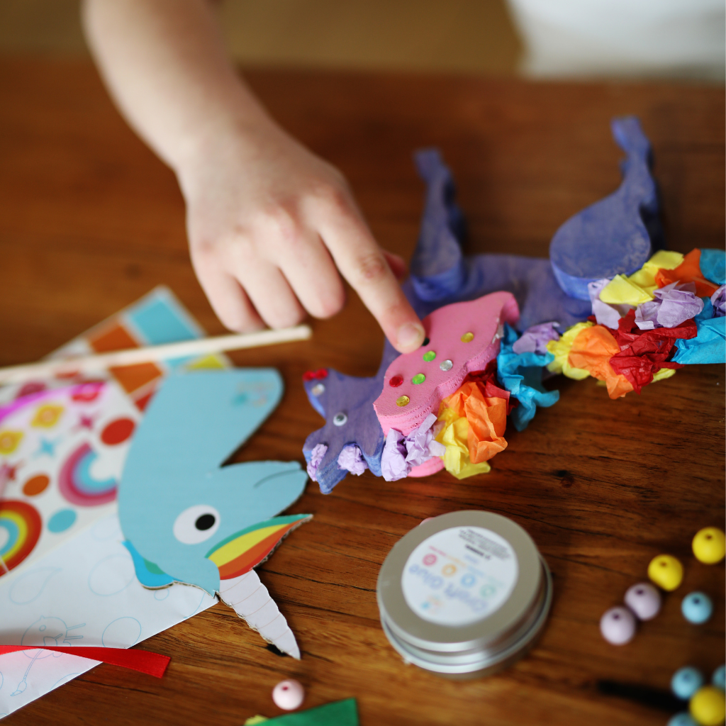 Child hand pointing to a crafted unicorn at a table setting.