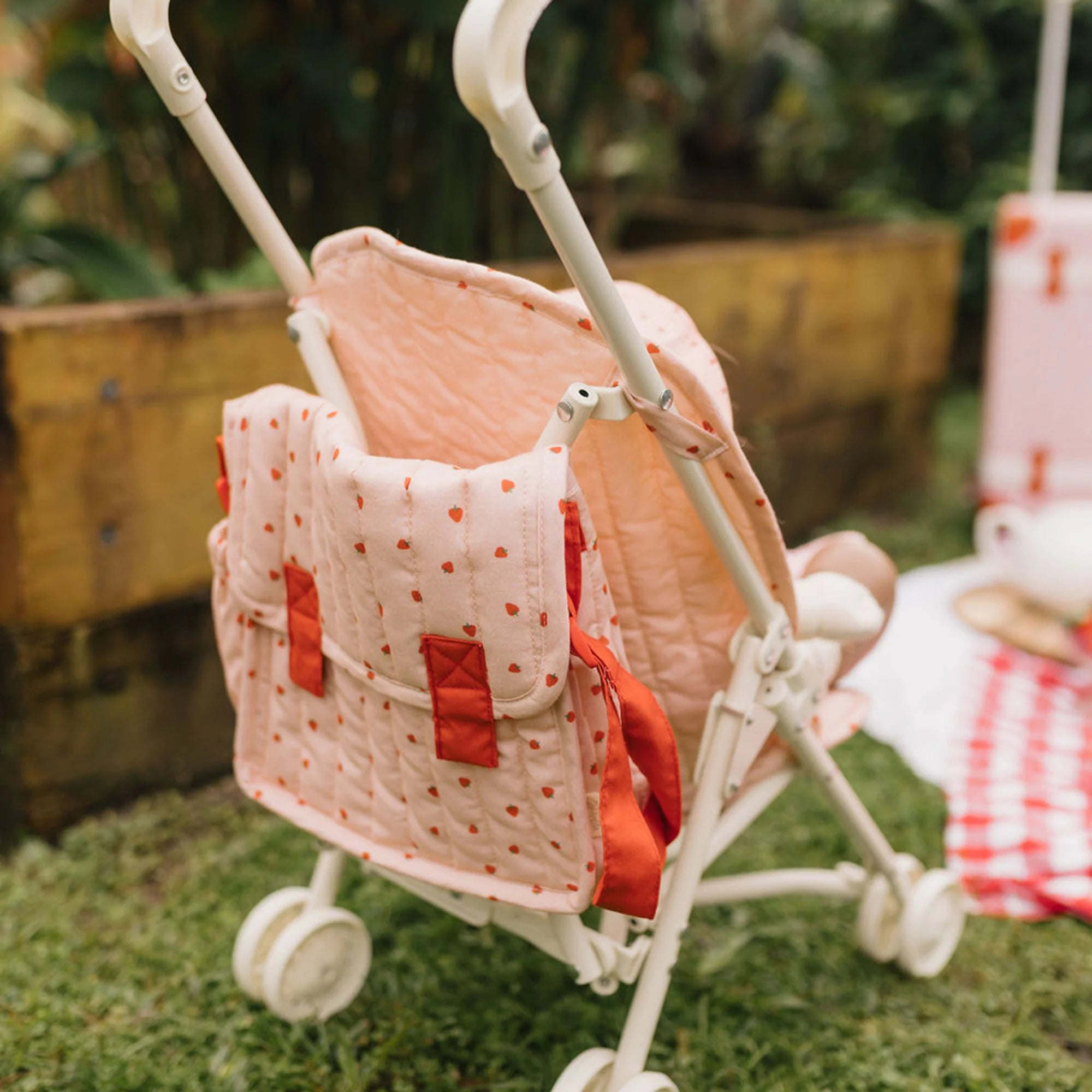 Pink baby buggy with red accents on a grassy outdoor setting