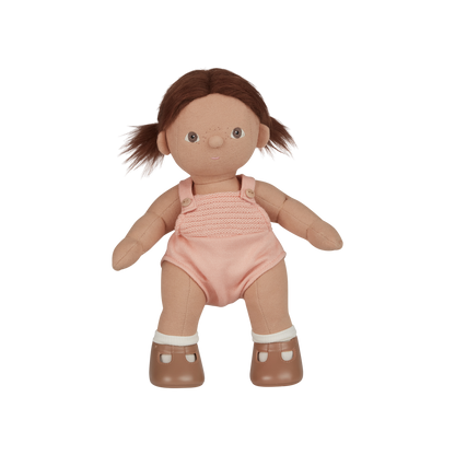Toy doll with brown hair, pink romper, and white shoes on a white background