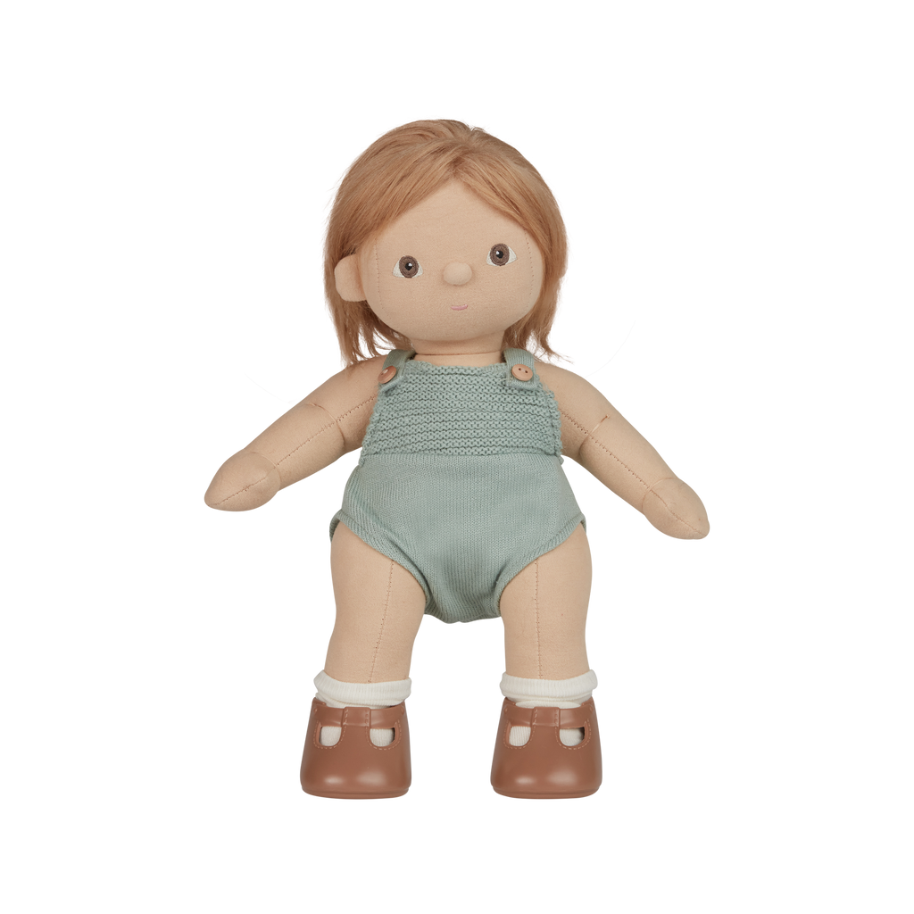 Doll with blonde hair wearing a green romper on a white background