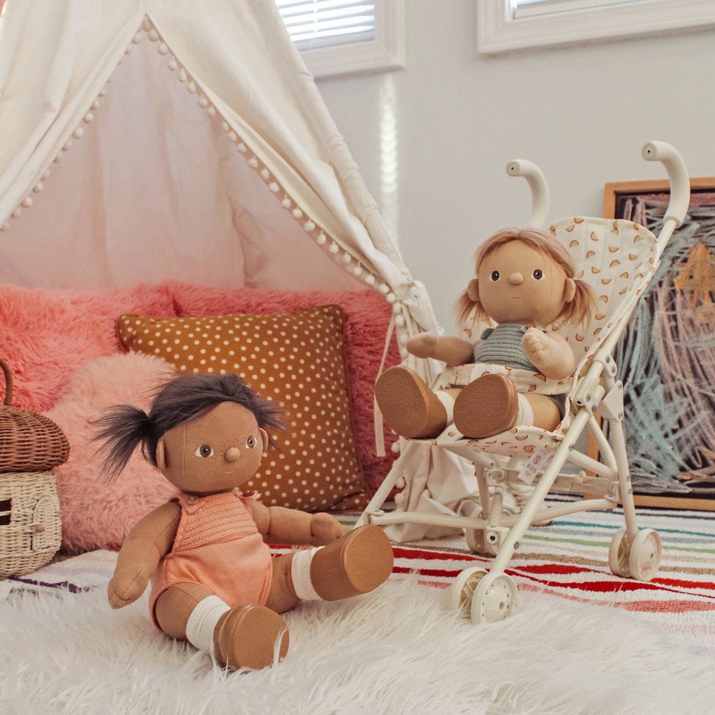 Two dolls in a child's bedroom with a canopy bed and colorful pillows.