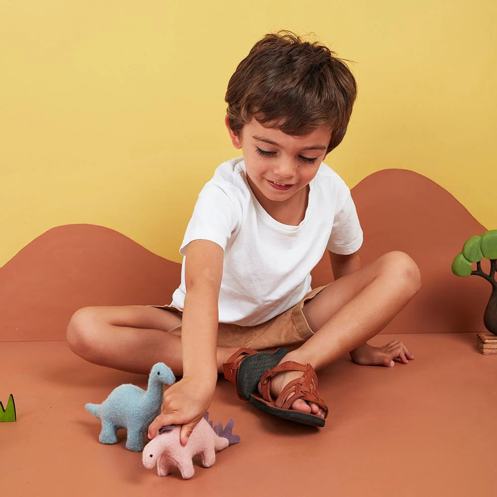 Child playing with dinosaur plush on an orange and yellow background.