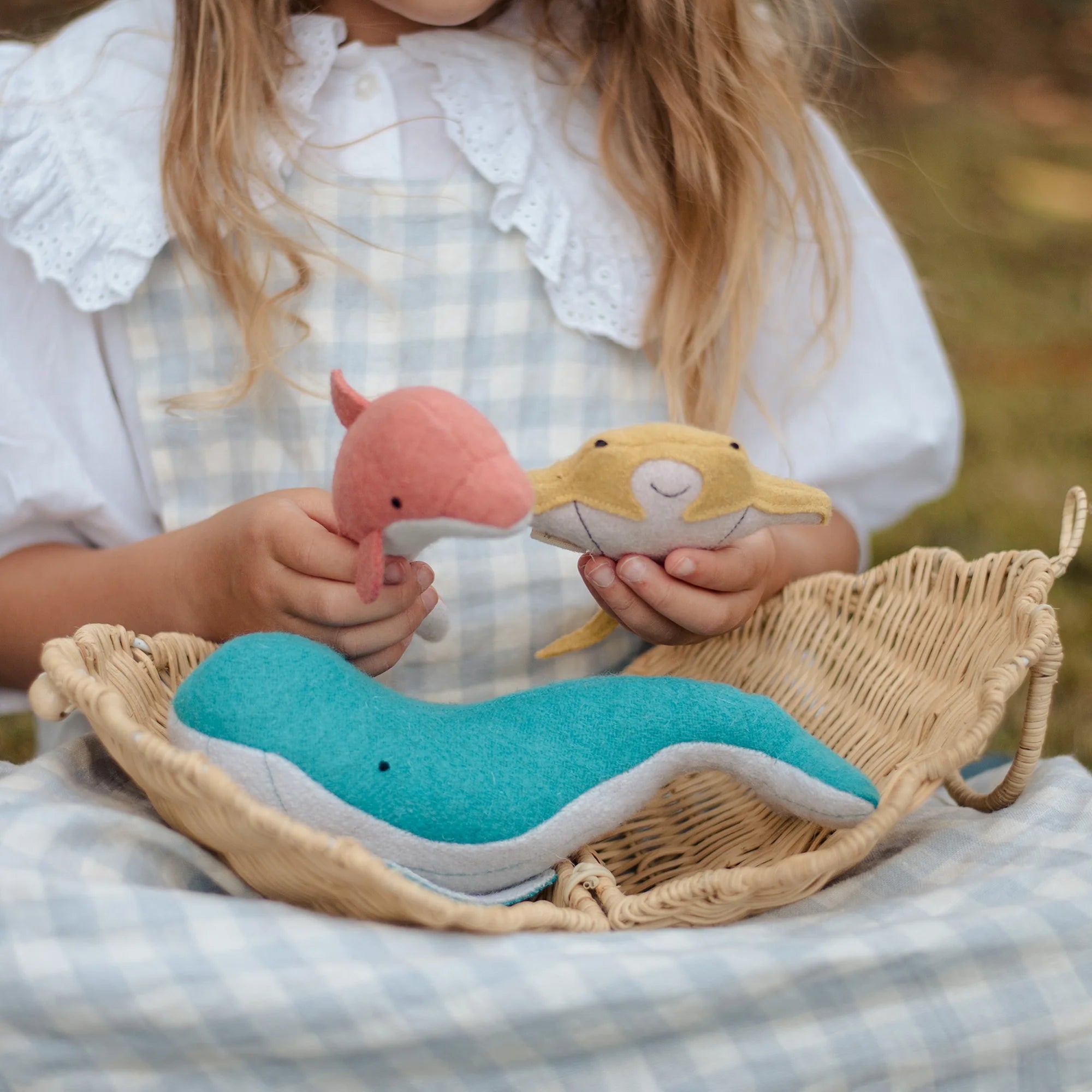 Child holding ocean animals in an outdoor setting.