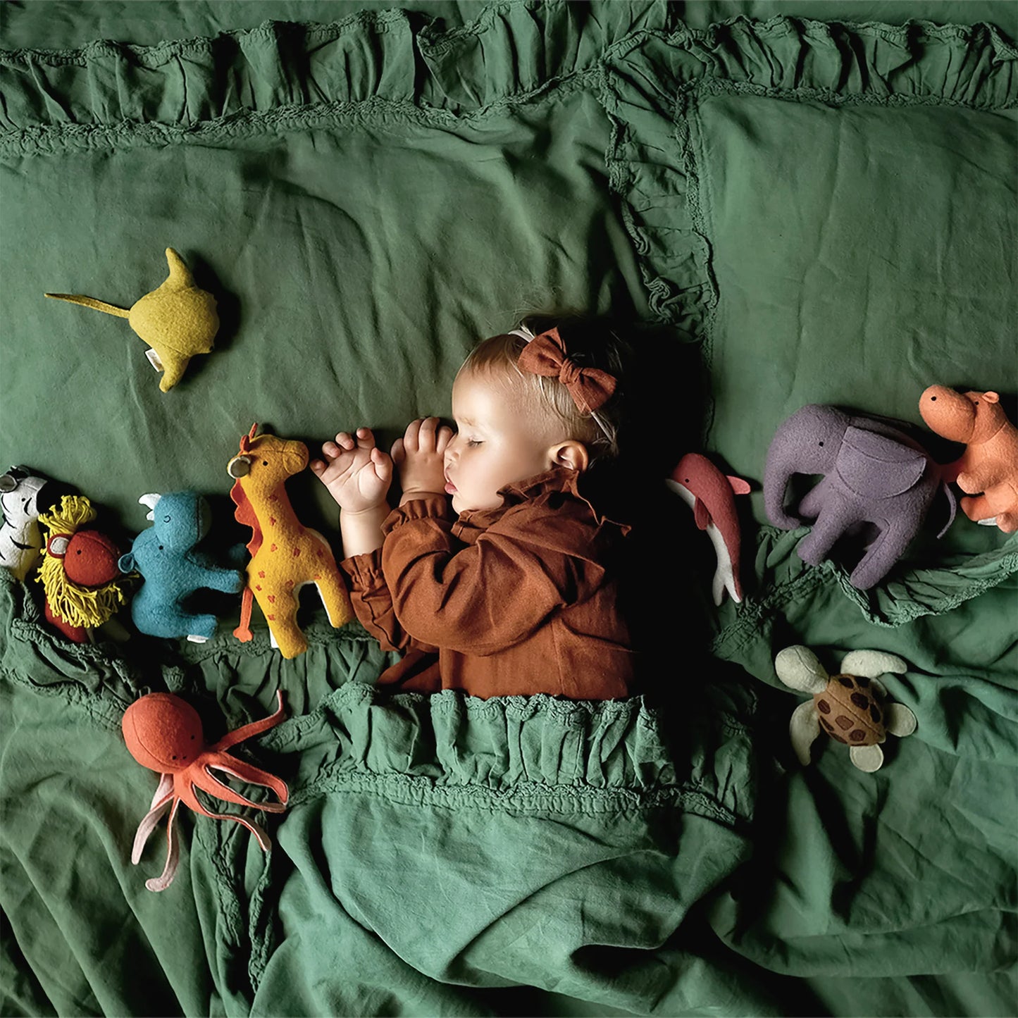 Child sleeping in bed with plush animals