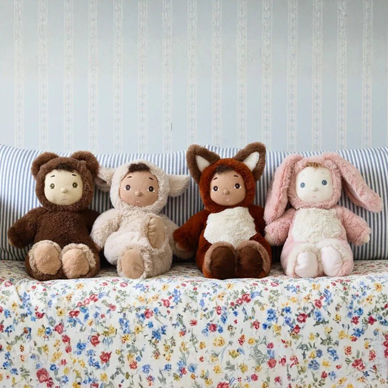 Four plush toys in animal costumes sitting on a floral-patterned blanket with a striped background.