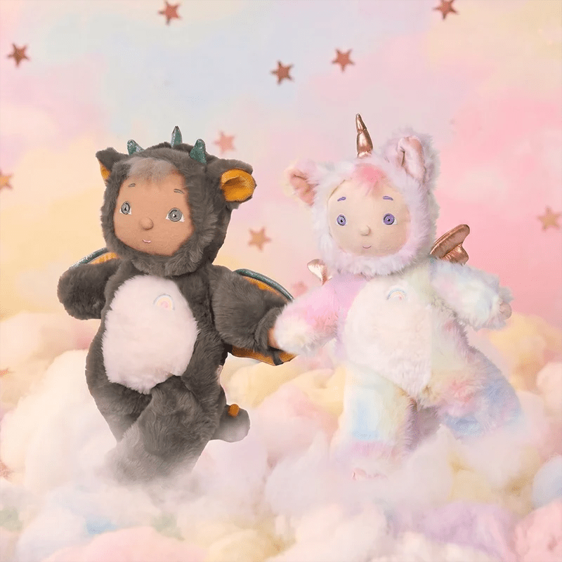 Two plush toys, one resembling a dragon and the other a unicorn, on a cloud-like surface with a starry background.
