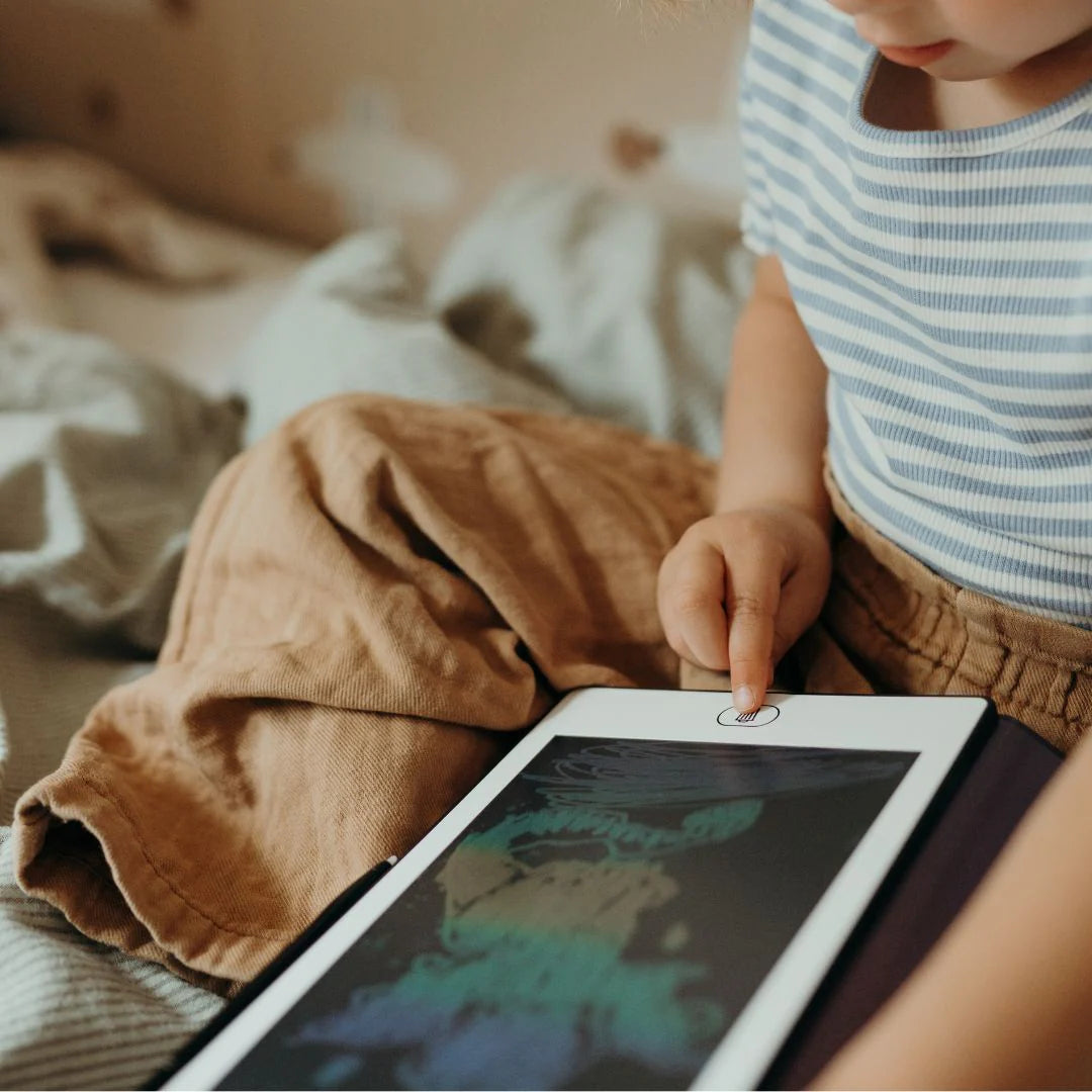 Child interacting with a tablet on a bed