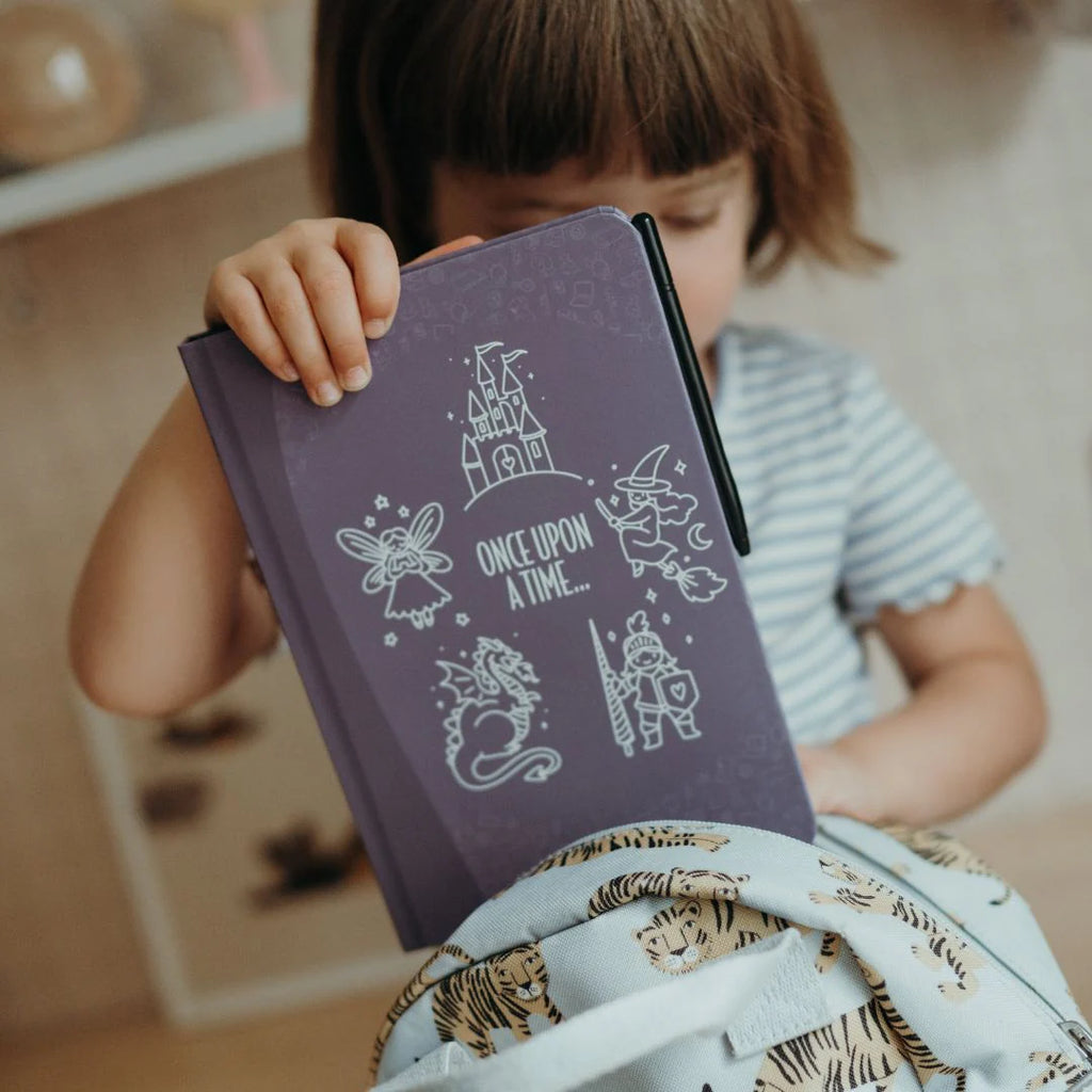 Child holding a purple notebook with fairy tale illustrations
