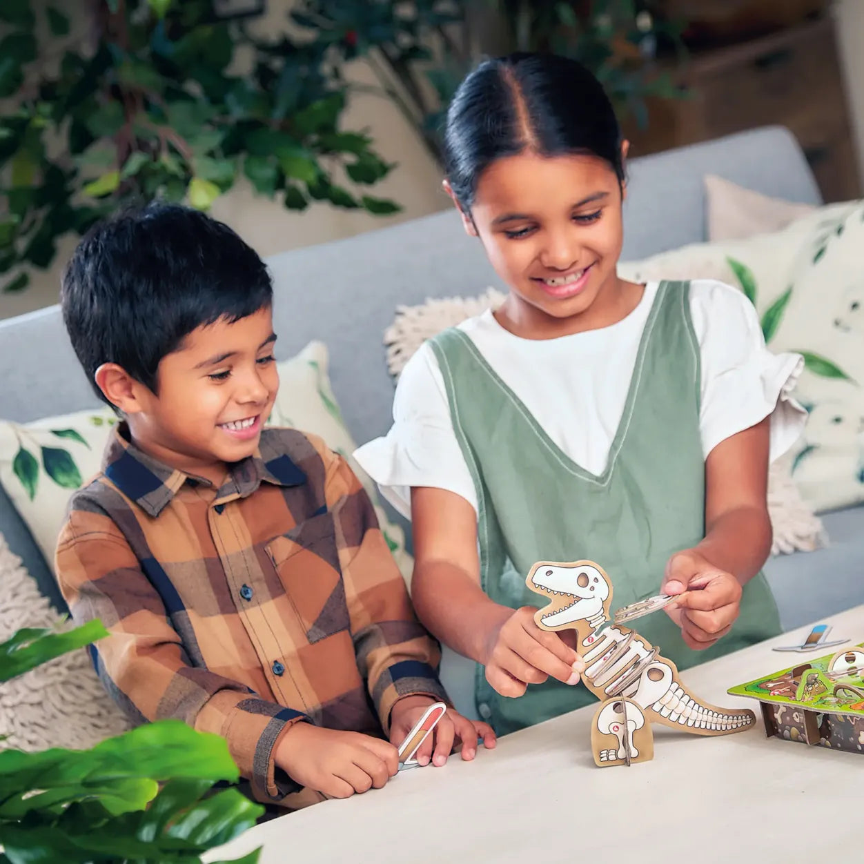 Two children playing with dinosaur toys on a couch