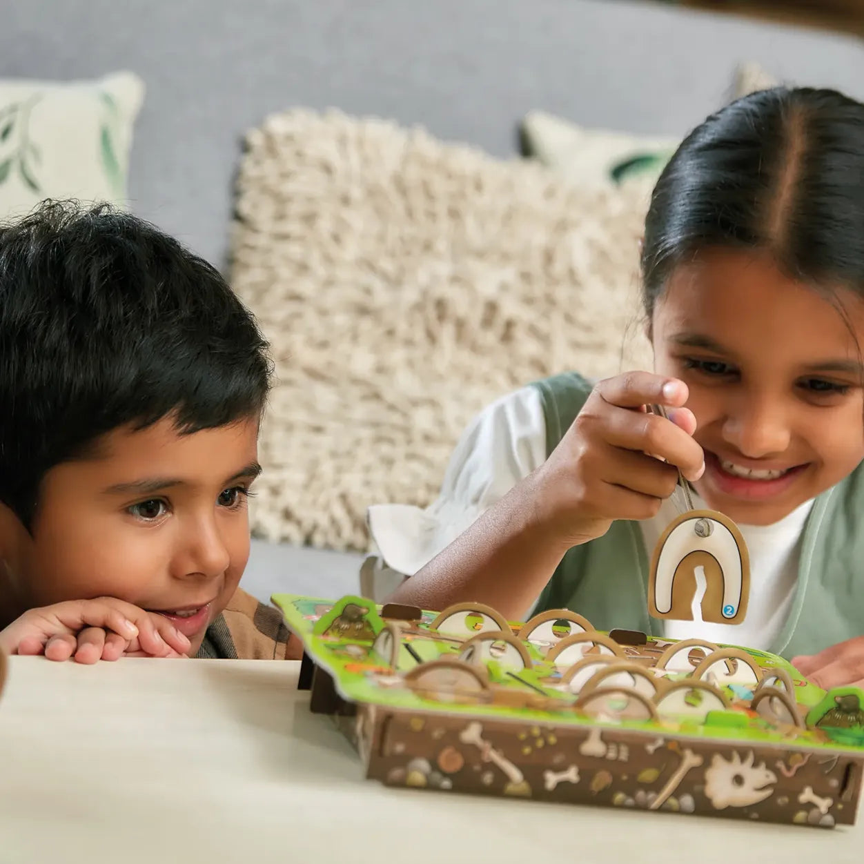 Two children playing with a board game on a couch