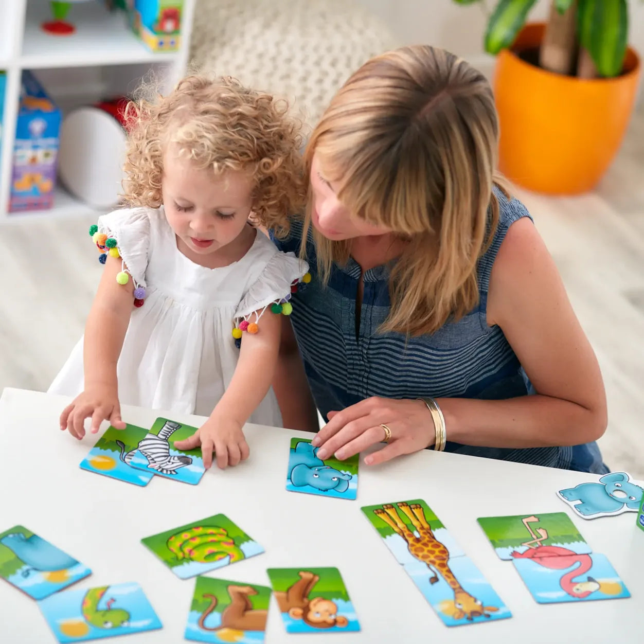 Woman and child playing with educational animal cards on a table