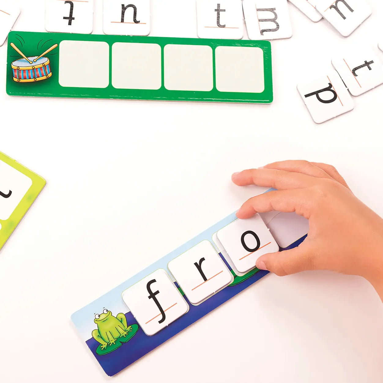 Child's hand interacting with a letter board and magnetic letters on a white surface.