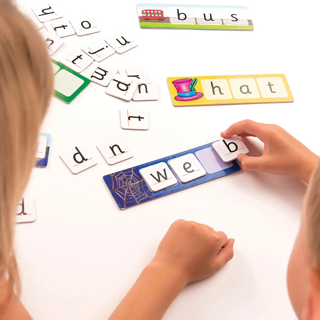 Children playing with letter tiles on a white surface