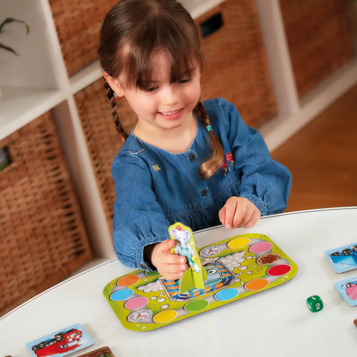 Young girl playing with a colorful game board and cards indoors.