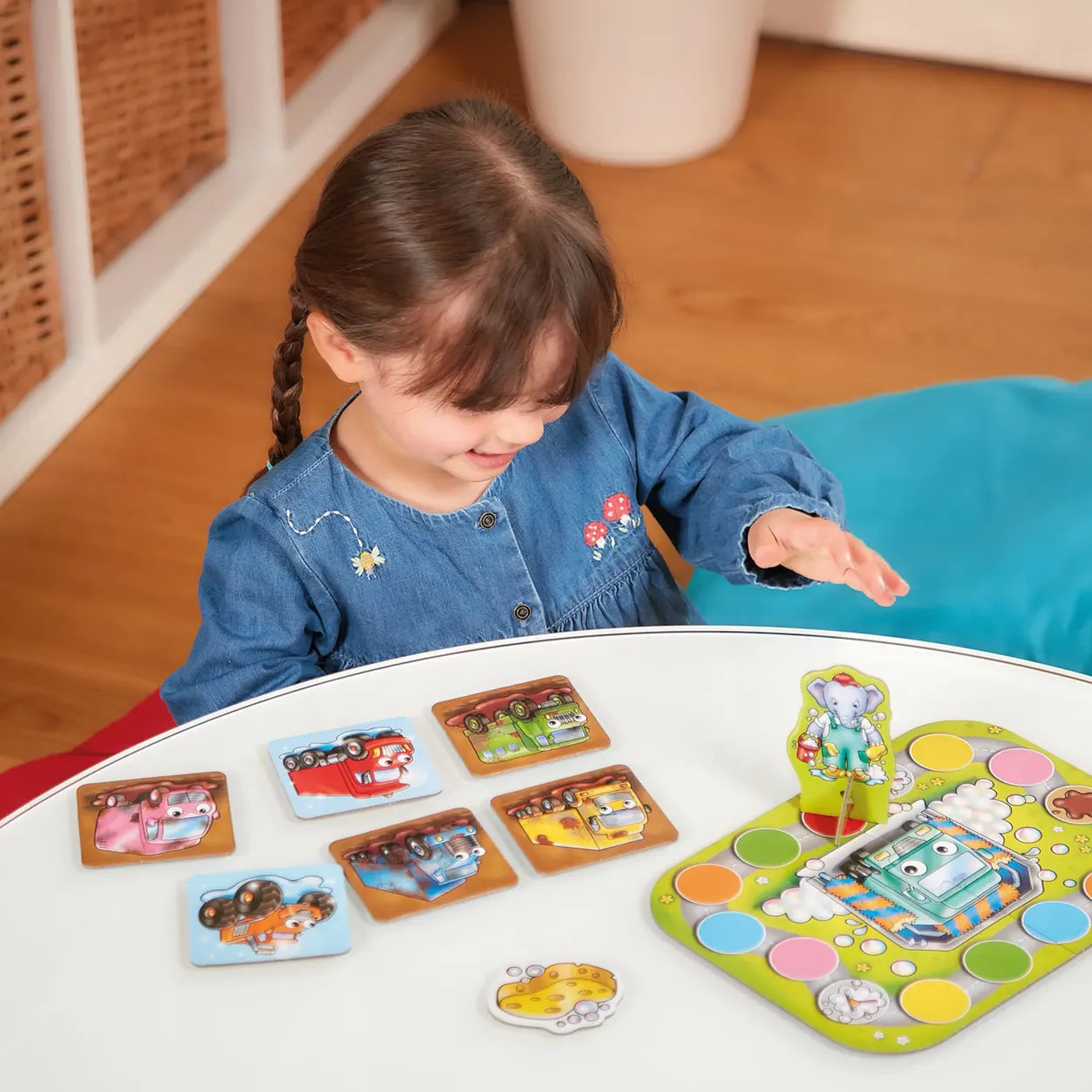 Child playing with a colorful board game on a white table.