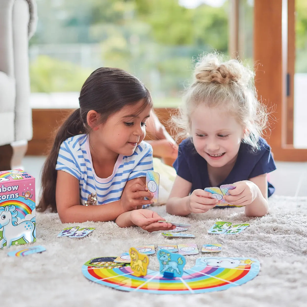 Two young girls playing with a colorful board game on a carpeted floor.