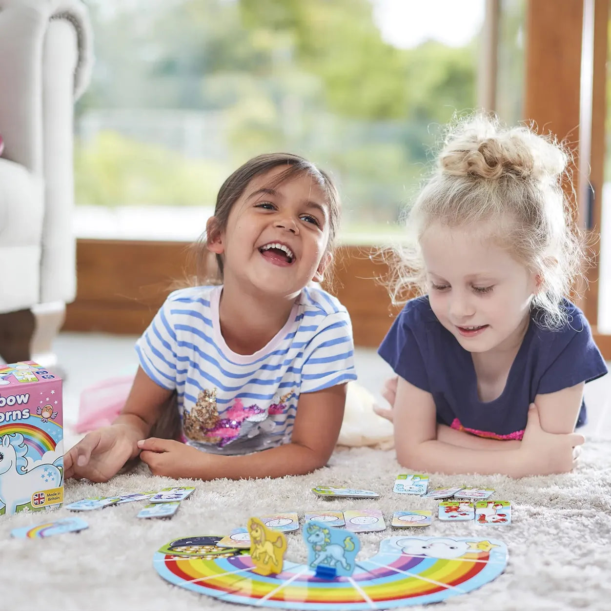 Two young girls playing with a board game on the floor.