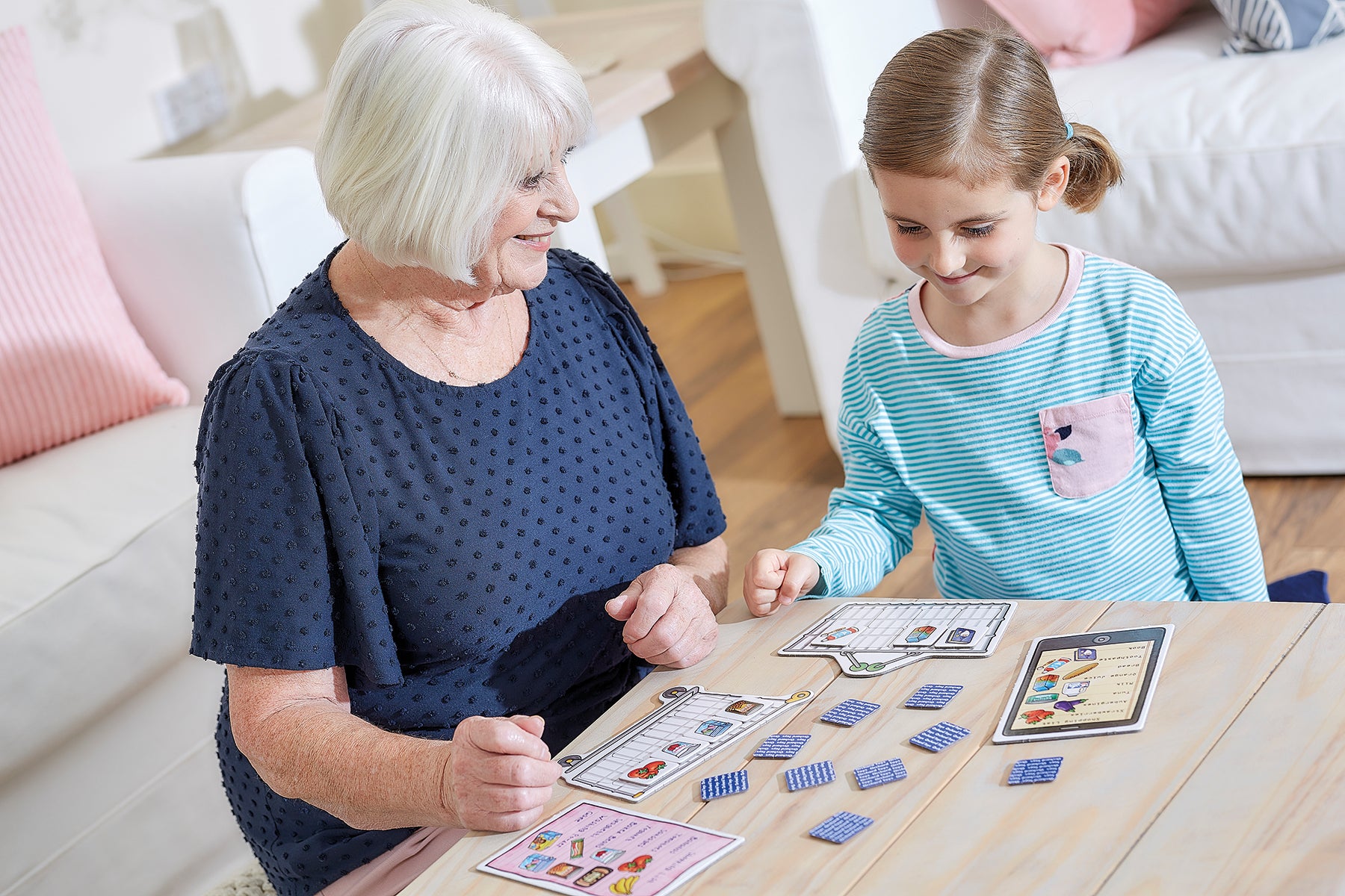 Grandmother and granddaughter playing a board game together in a cozy living room.