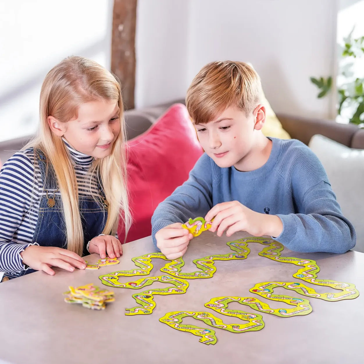 Two children playing with a board game on a table.