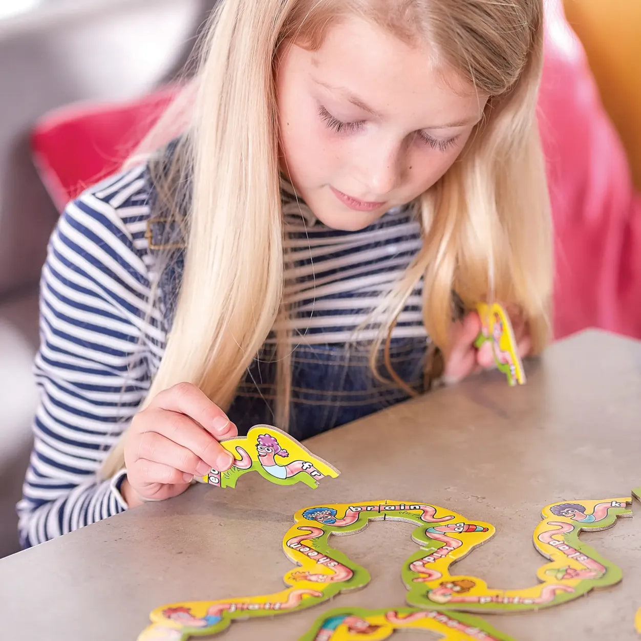 Young girl playing with colorful paper shapes at a table.