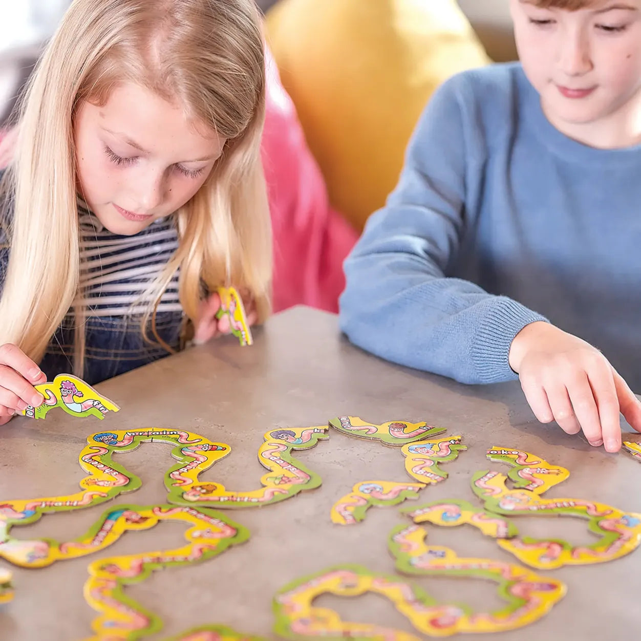 Two children playing with colorful snake-like toys on a table.