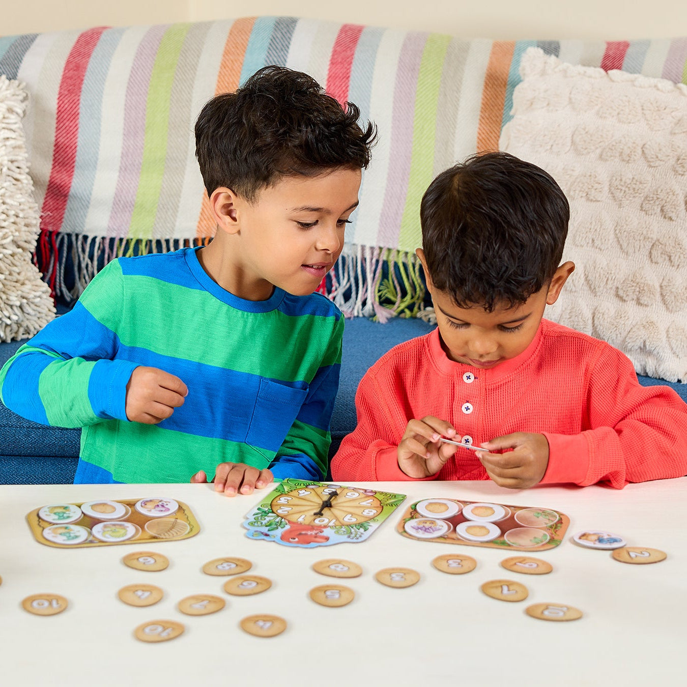 Two children playing with a board game on a table in a living room.