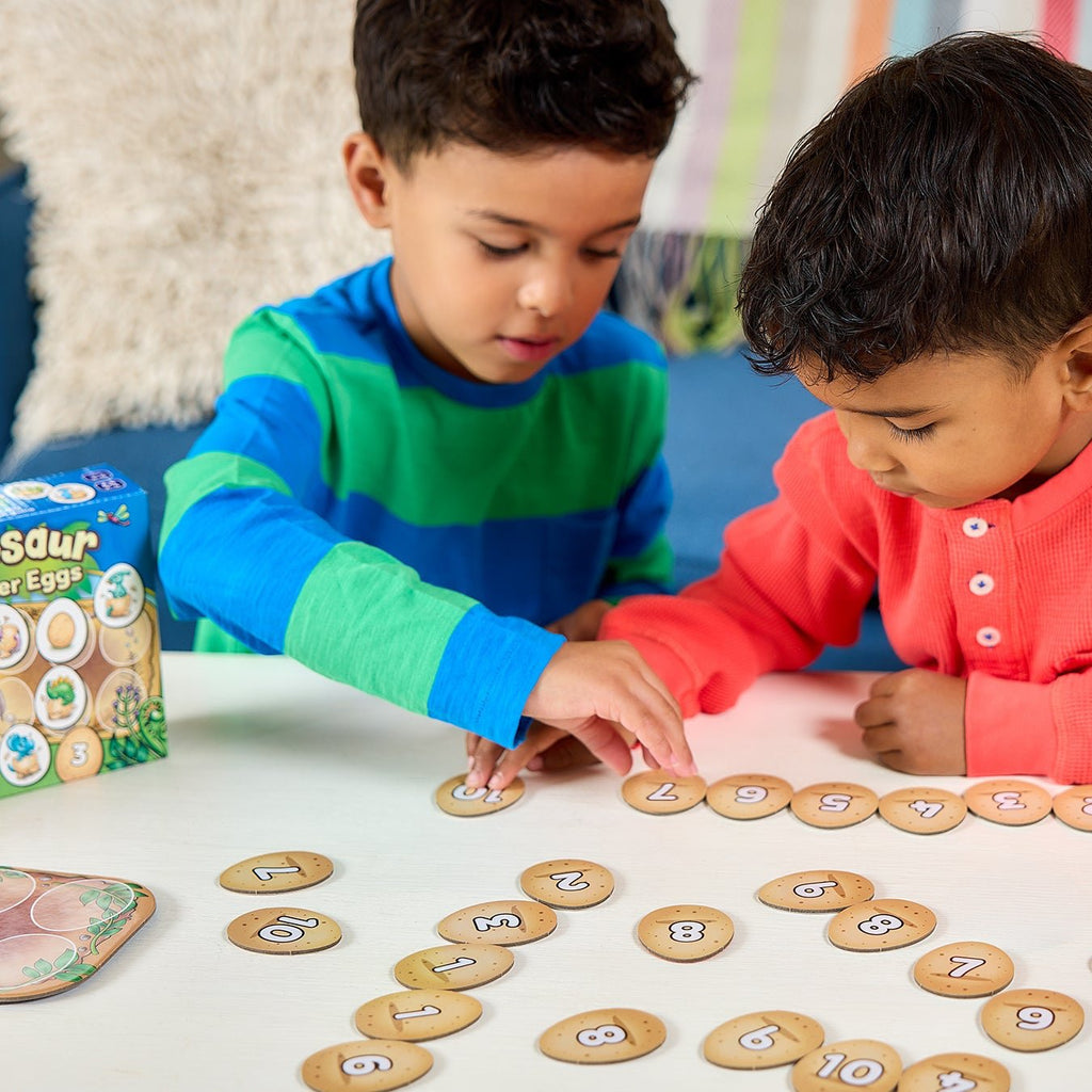 Two children playing with a number game on a table.
