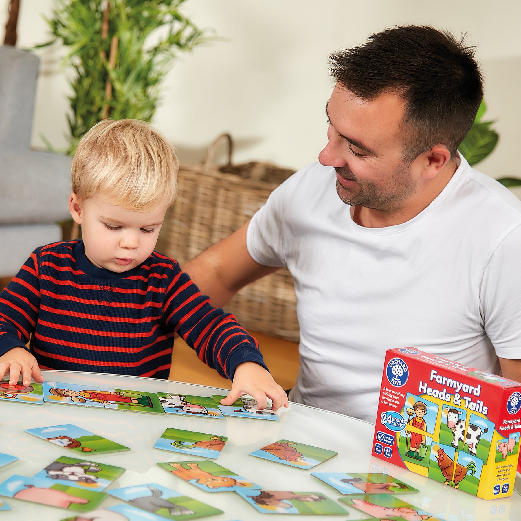 Man and child playing with a 'Farmyard Heads & Tails' puzzle game