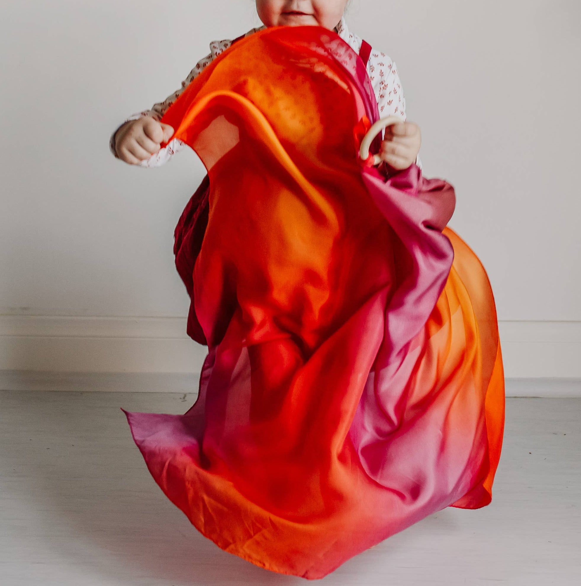 Child in a vibrant orange and red dress against a plain background