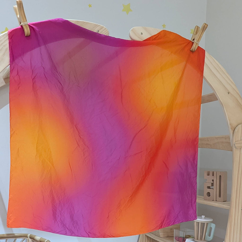 Colorful tie-dye cloth hanging on a wooden rack in a room with toys and furniture.
