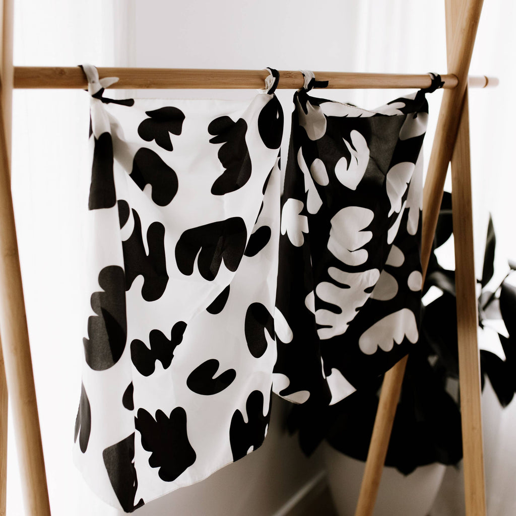 Black and white patterned towels hanging on a wooden rack against a white wall.