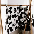 Black and white patterned towels hanging on a wooden rack against a white wall.