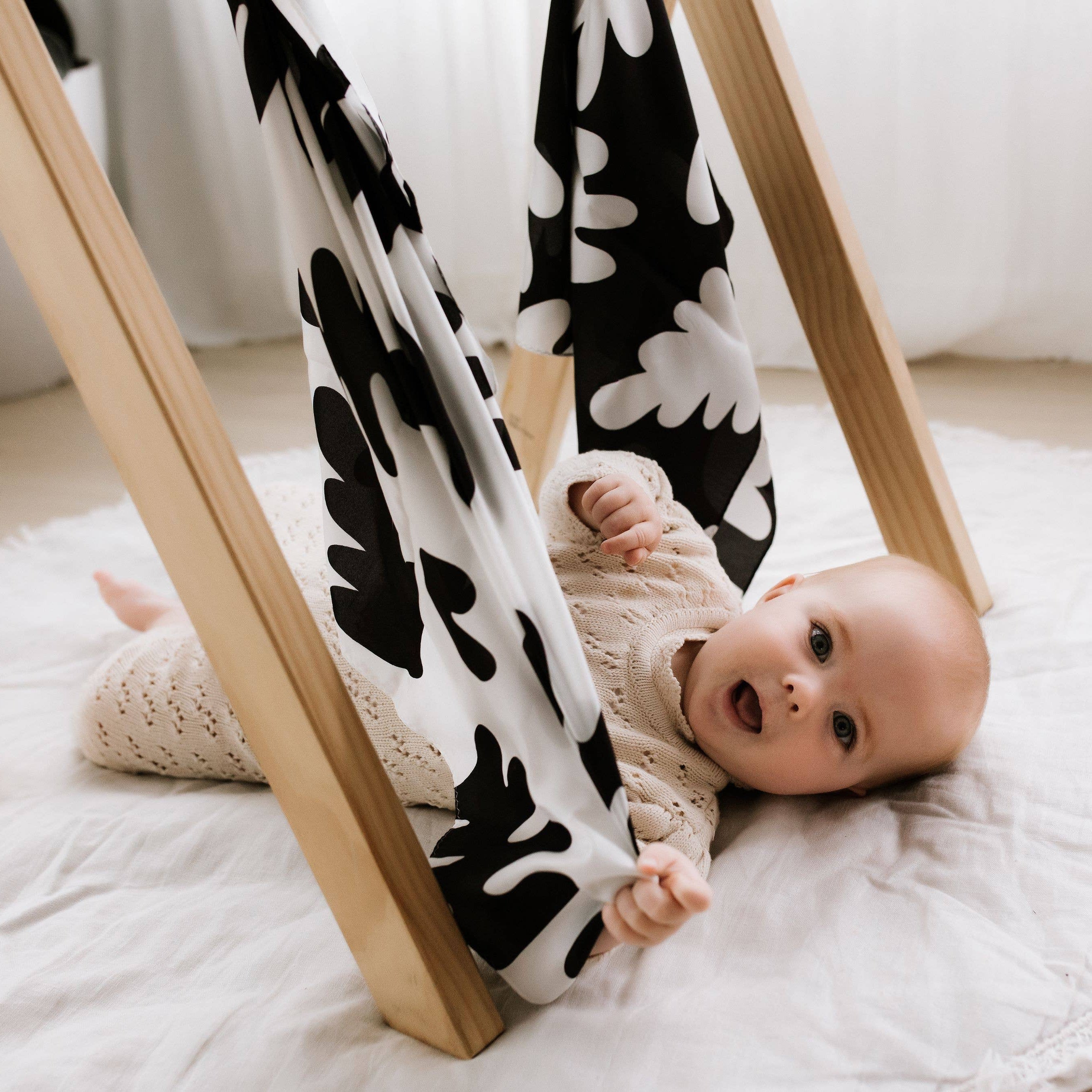 Baby lying on a white rug with a black and white patterned hammock