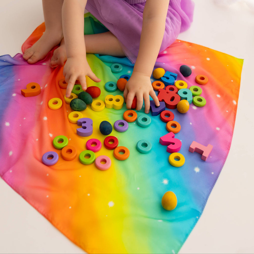 Child playing with colorful alphabet letters on a rainbow mat