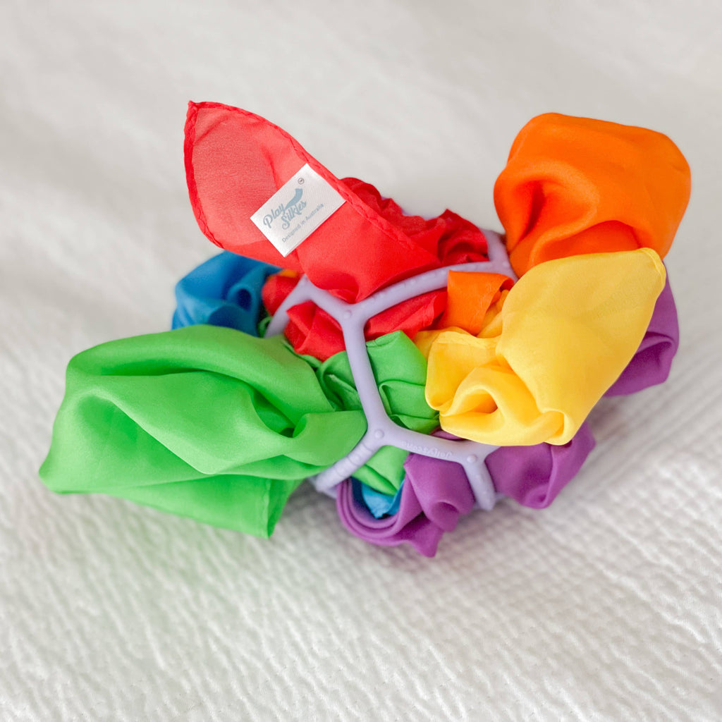 Colorful silks arranged in a circular pattern on a white fabric background