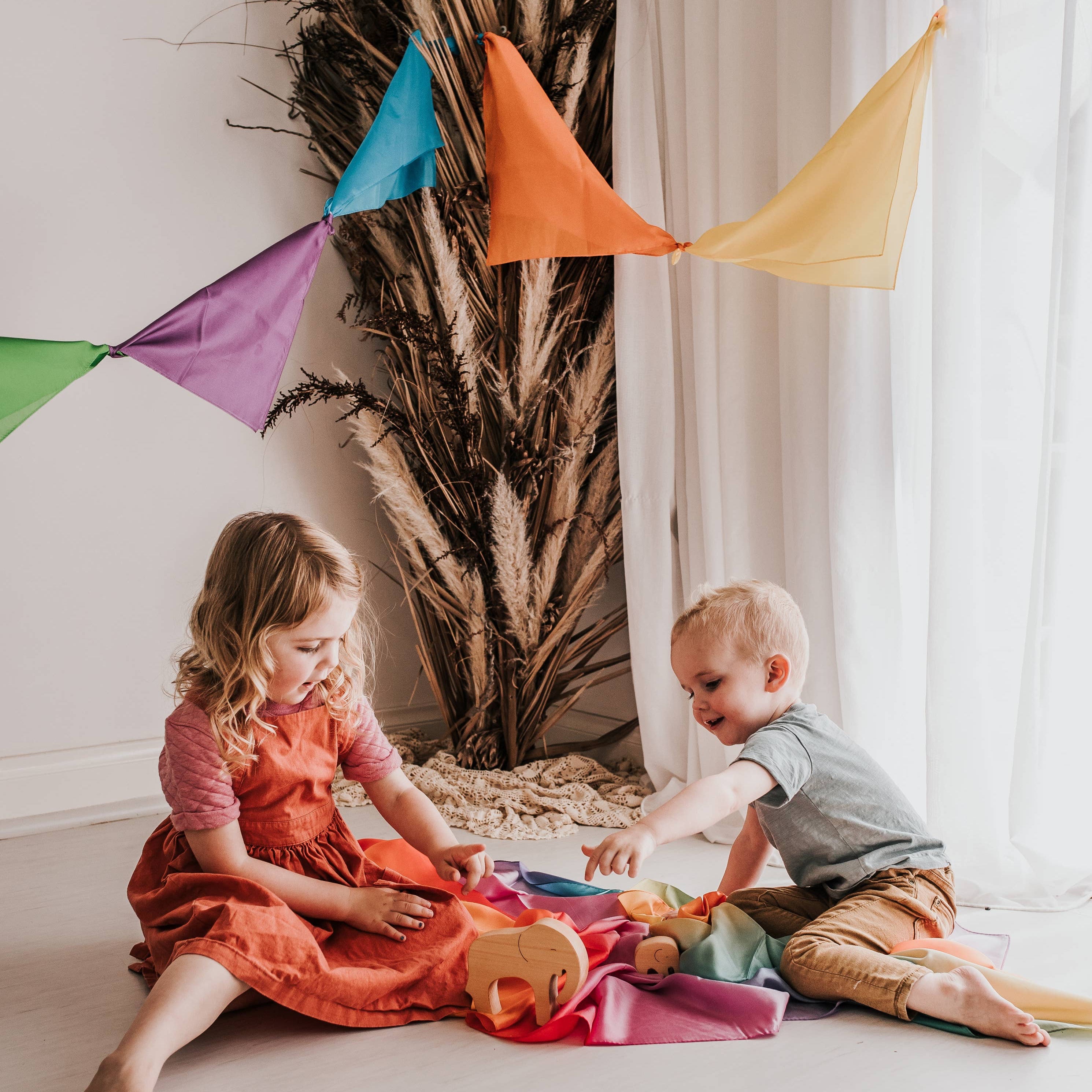 Two children playing on the floor with colorful flags in the background