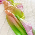 Colorful fabric with pink, green, and orange gradient on a textured white background