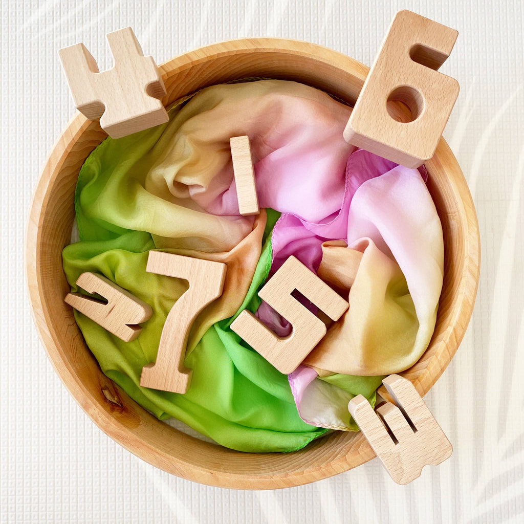 Wooden numbers in a bowl with colorful slime on a white background