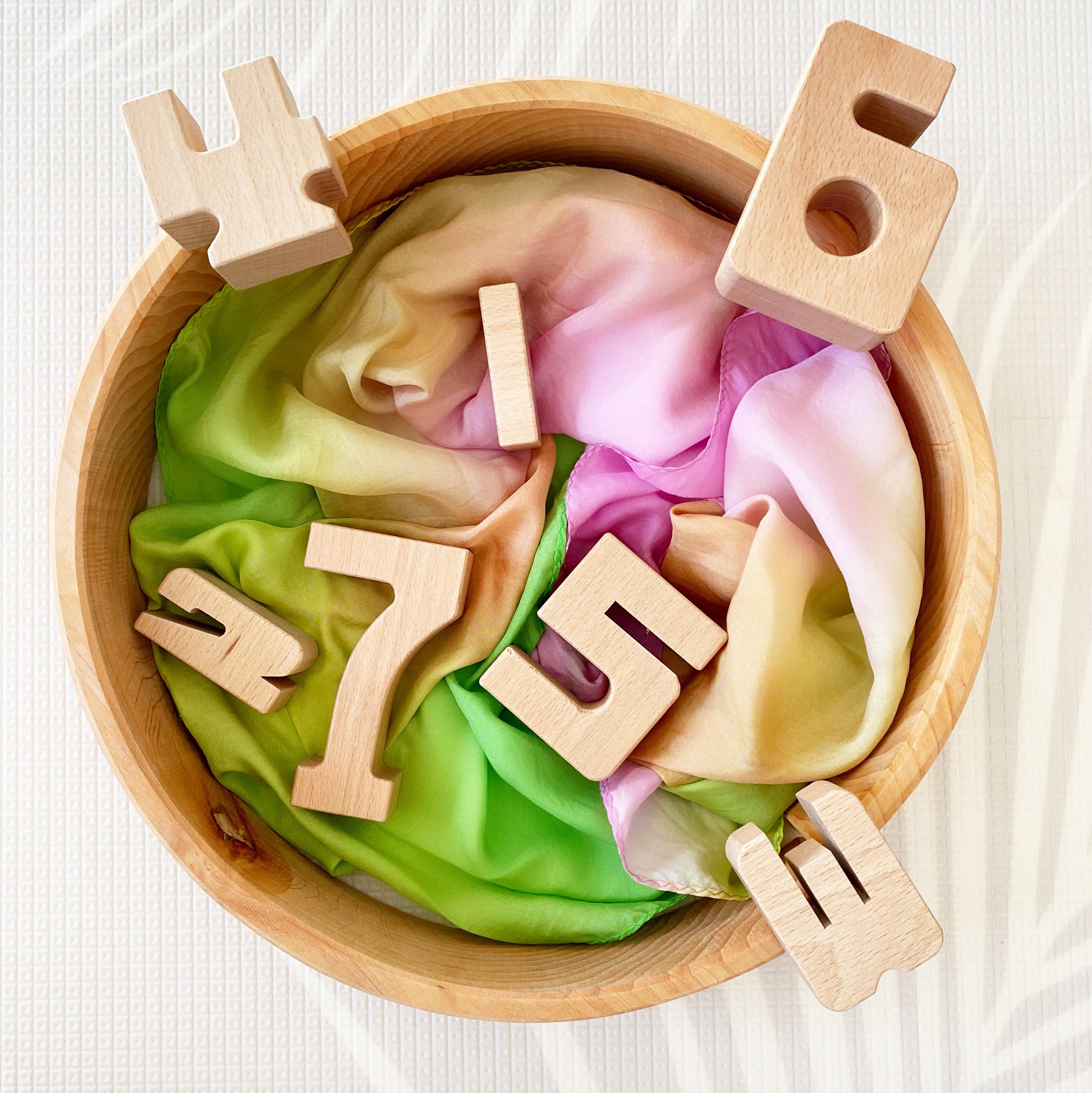 Wooden numbers in a bowl with colorful slime on a white background