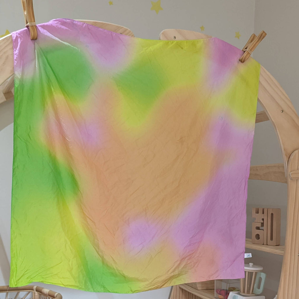 Colorful tie-dye cloth on a wooden rack in a room with toys and furniture.