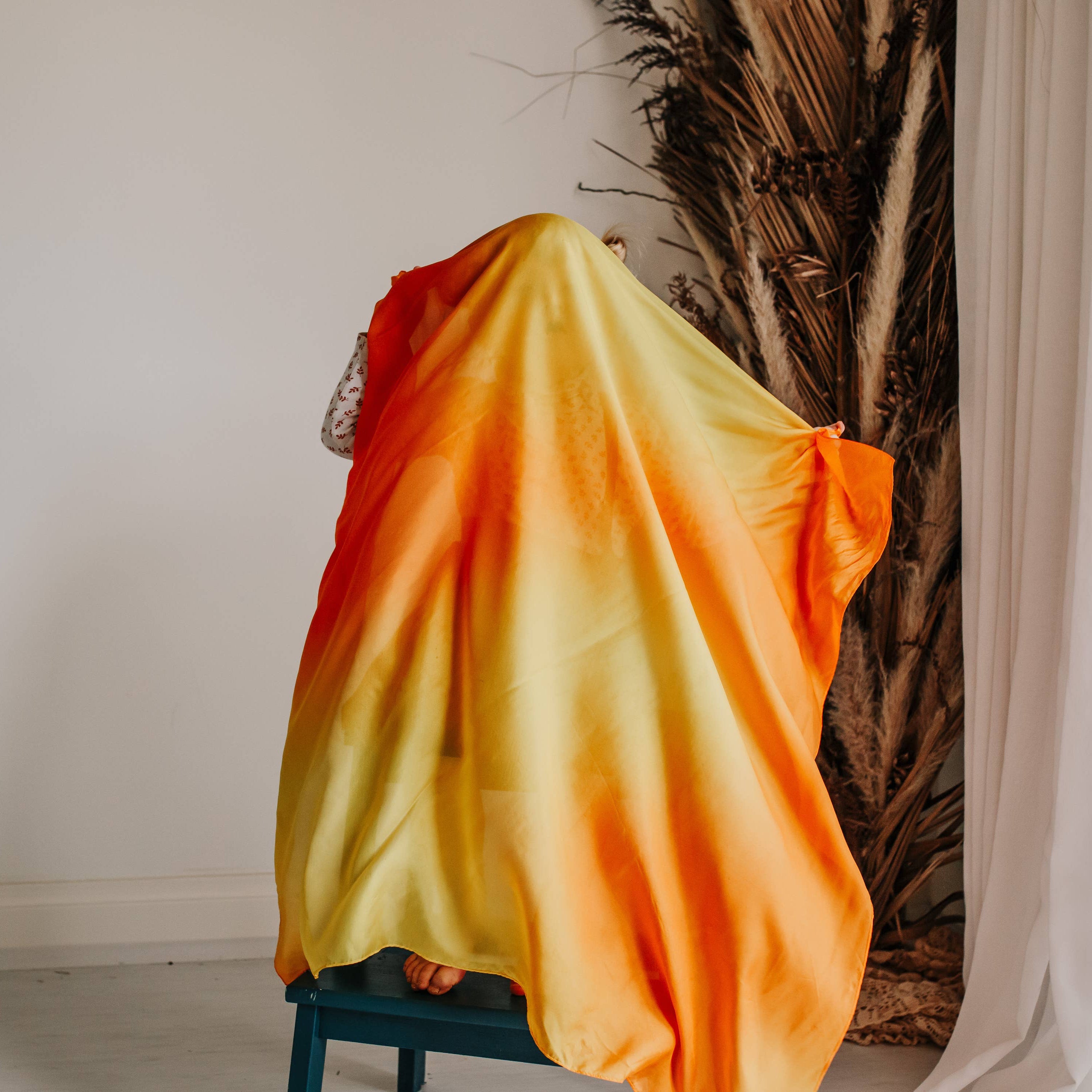 Person wearing a bright orange and yellow gradient garment in a minimal indoor setting.