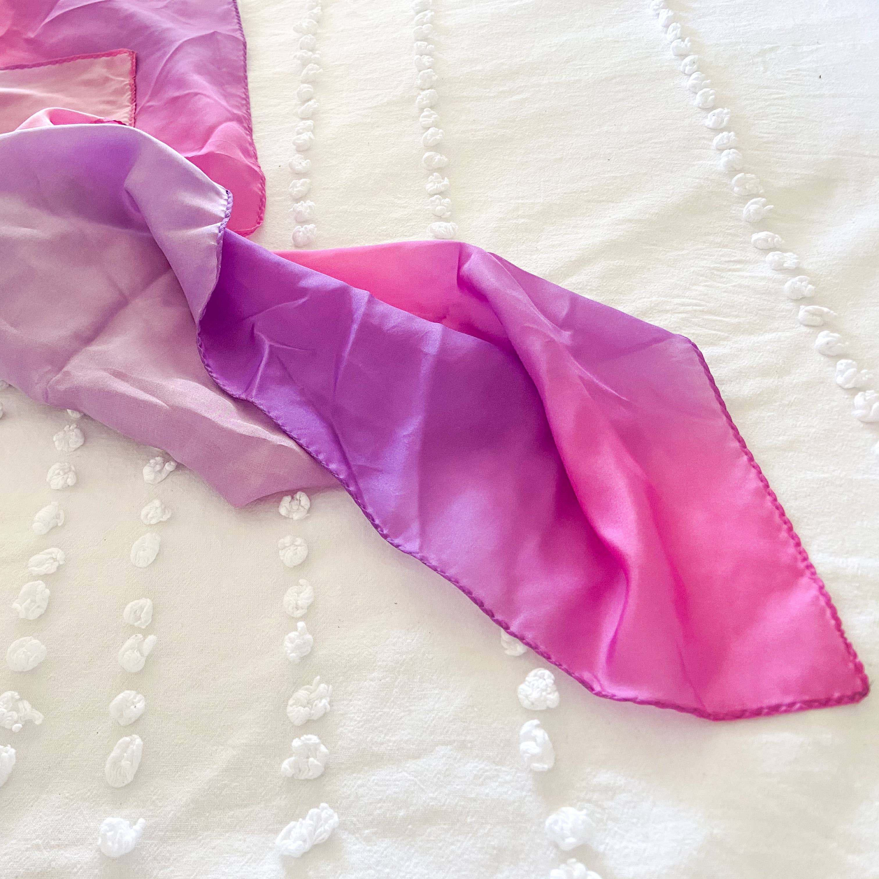 Gradient pink to purple fabric on a textured white surface