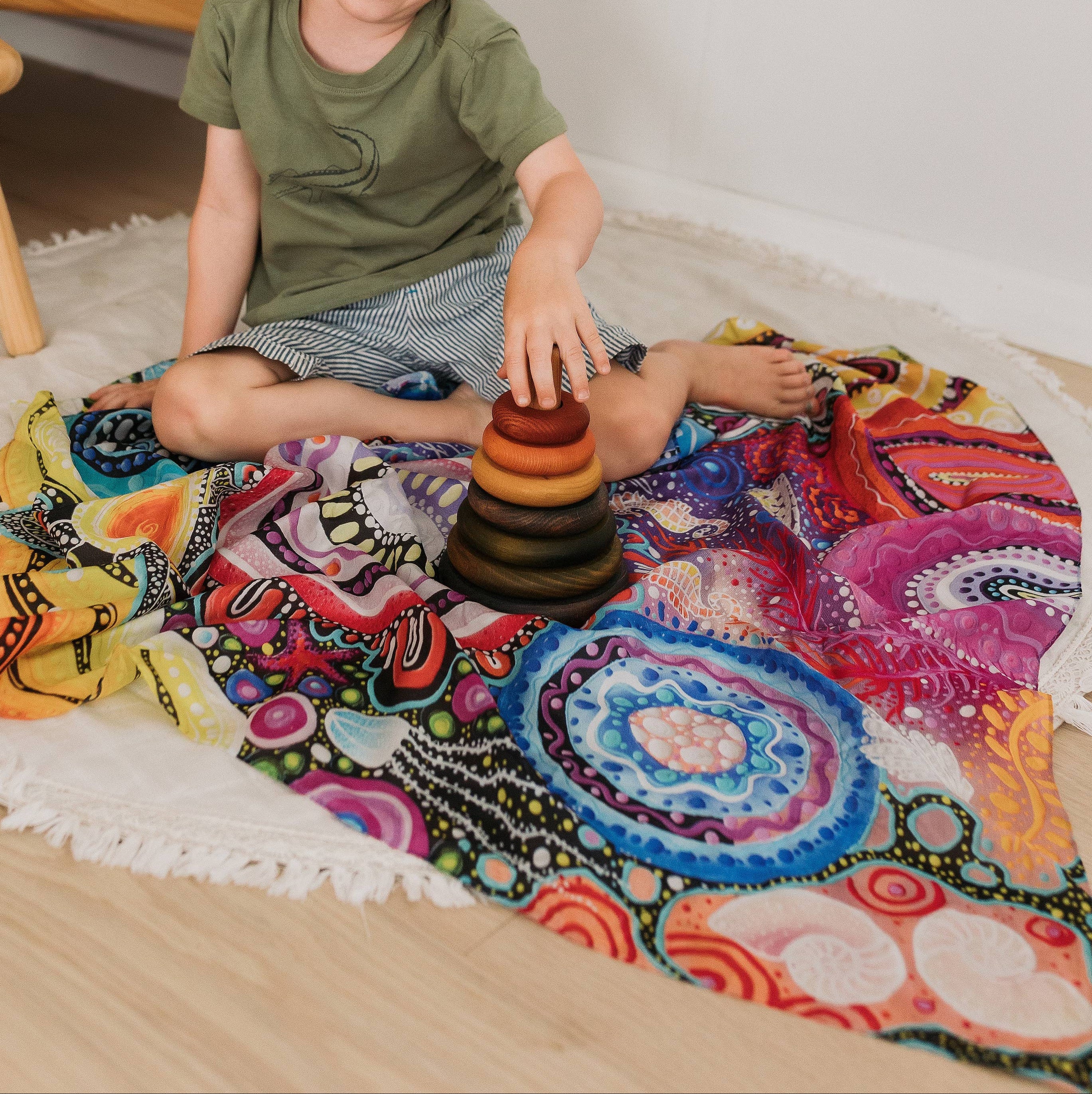Child playing with wooden toys on a colorful rug in a cozy room.