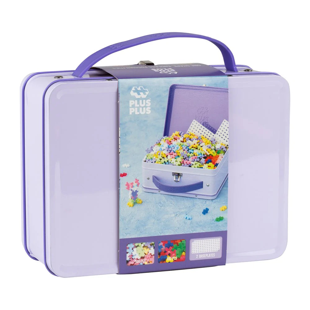 A metal suitcase-shaped toy box with a purple handle and label showing the product name and piece count, 600 pieces, in a pastel color scheme. The box is closed and displayed against a white background.