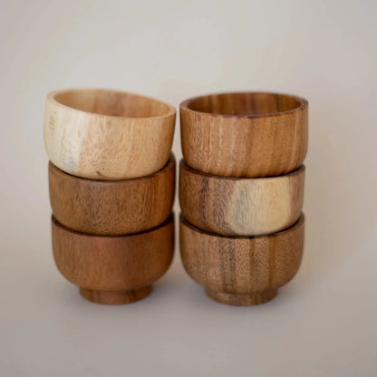 A set of six stacked mini wooden bowls with varying shades and grain patterns.