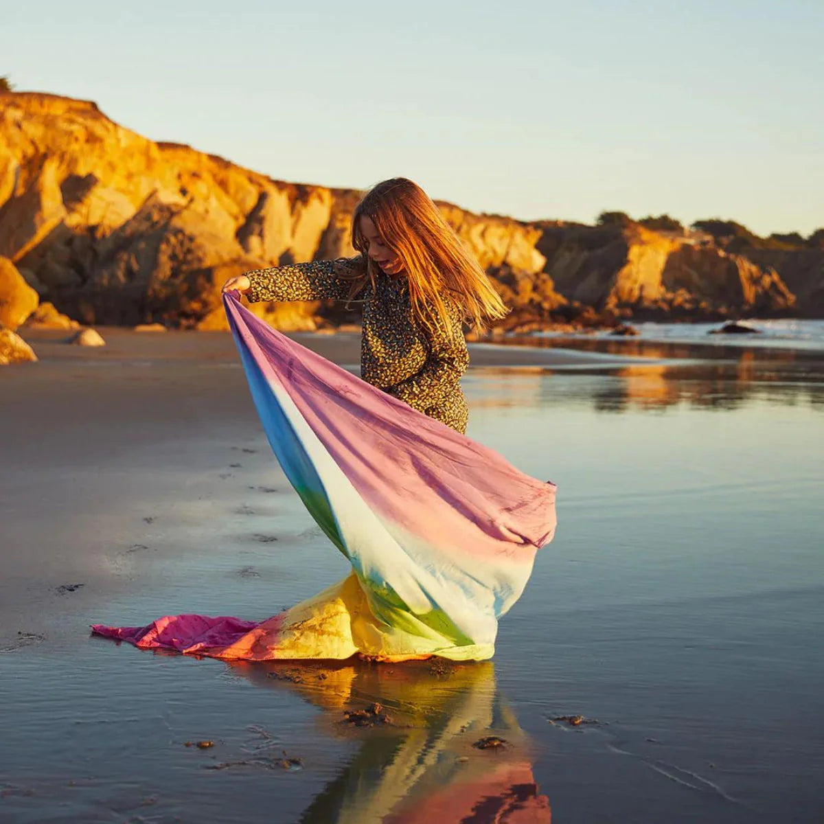 Child with a colorful scarf on a beach at sunset